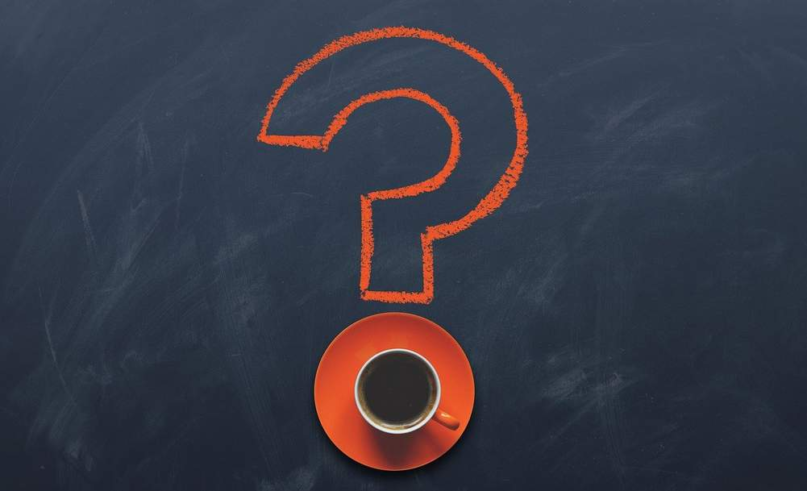 Question mark drawn on a chalkboard next to a cup of coffee